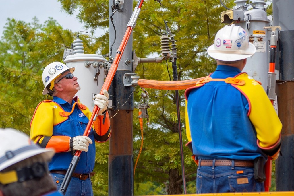 Eletricistas trabalhando em altura com equipamento de segurança